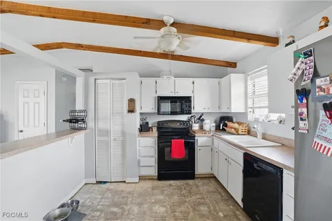 a kitchen with stainless steel appliances granite countertop a refrigerator a sink dishwasher a stove and white countertops with wooden floor