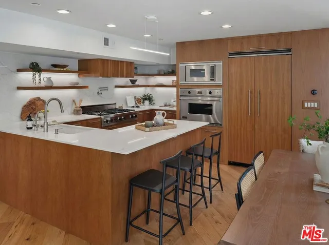a kitchen with stainless steel appliances a table chairs and a refrigerator