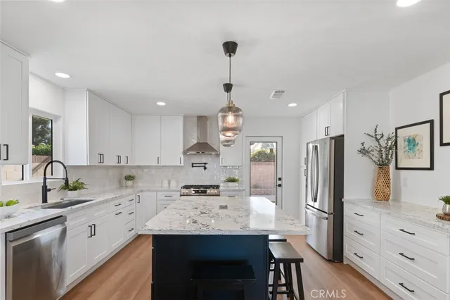 a kitchen with stainless steel appliances kitchen island granite countertop a sink refrigerator and cabinets