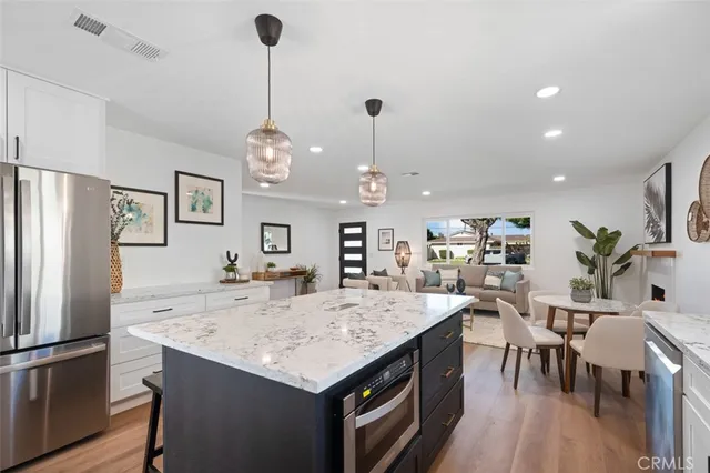 a large kitchen with kitchen island a refrigerator a stove a dining table and chairs with wooden floor