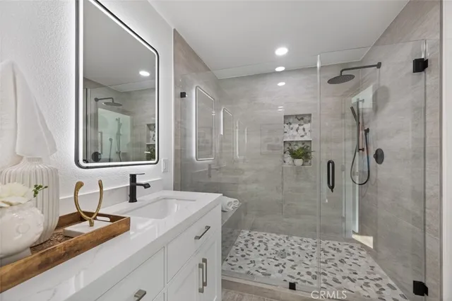 a bathroom with a granite countertop sink a toilet a mirror and shower