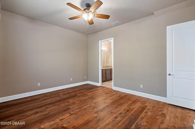 an empty room with wooden floor chandelier fan and windows