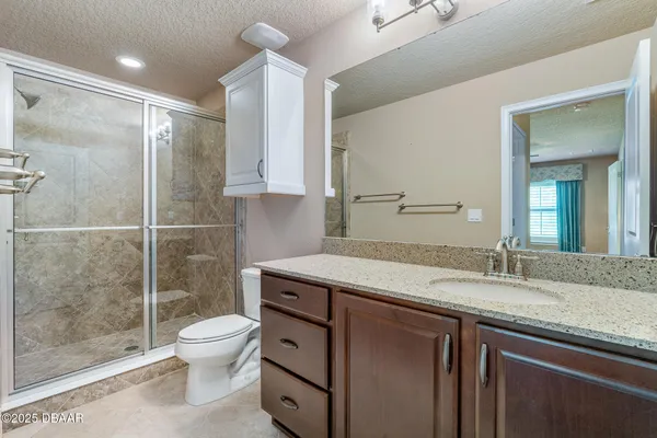 a bathroom with a granite countertop sink a toilet a mirror and shower