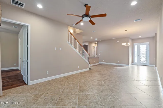 a view of an empty room with wooden floor and a ceiling fan