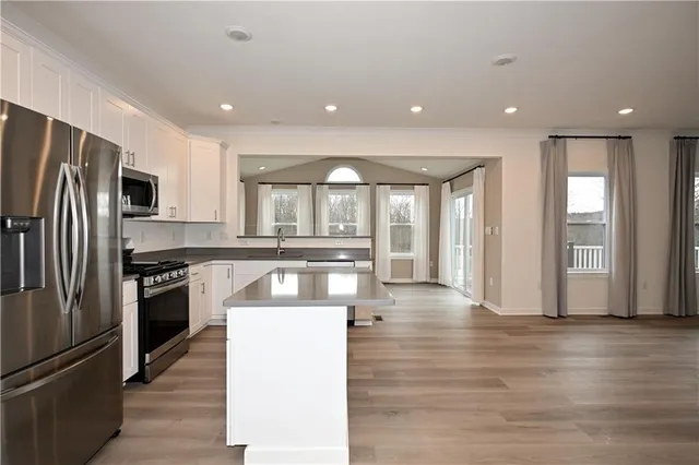 a kitchen with stainless steel appliances granite countertop a refrigerator a stove and a wooden floors