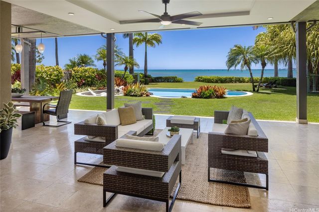 a view of a patio with couches potted plants and a big yard