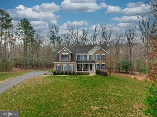 a view of a house with a big yard and large trees