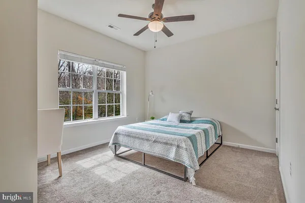 a bedroom with a bed couch and windows