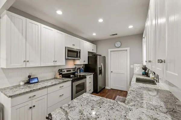 a kitchen with stainless steel appliances granite countertop a stove a sink and a refrigerator