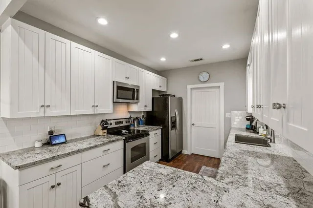 a kitchen with stainless steel appliances granite countertop a stove a sink and a refrigerator