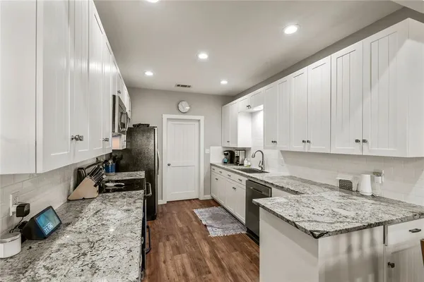 a kitchen with granite countertop kitchen island stainless steel appliances a stove refrigerator sink and cabinets