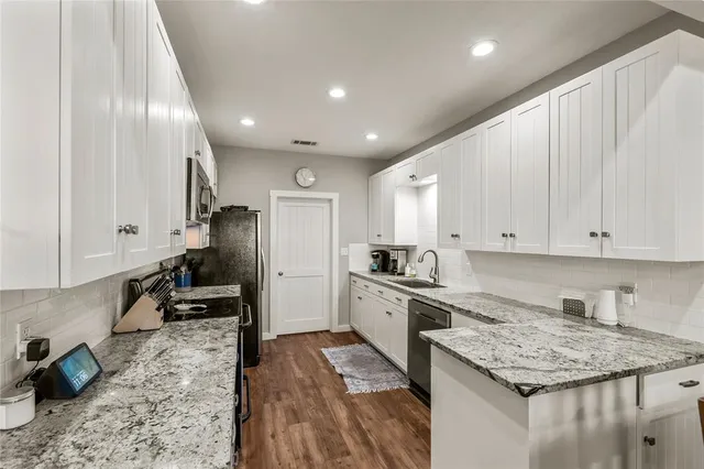 a kitchen with granite countertop kitchen island stainless steel appliances a stove refrigerator sink and cabinets