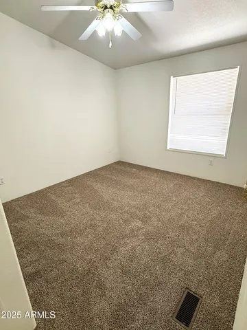 an empty room with a ceiling fan and window