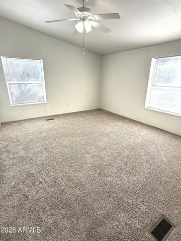 en empty room with windows and ceiling fan