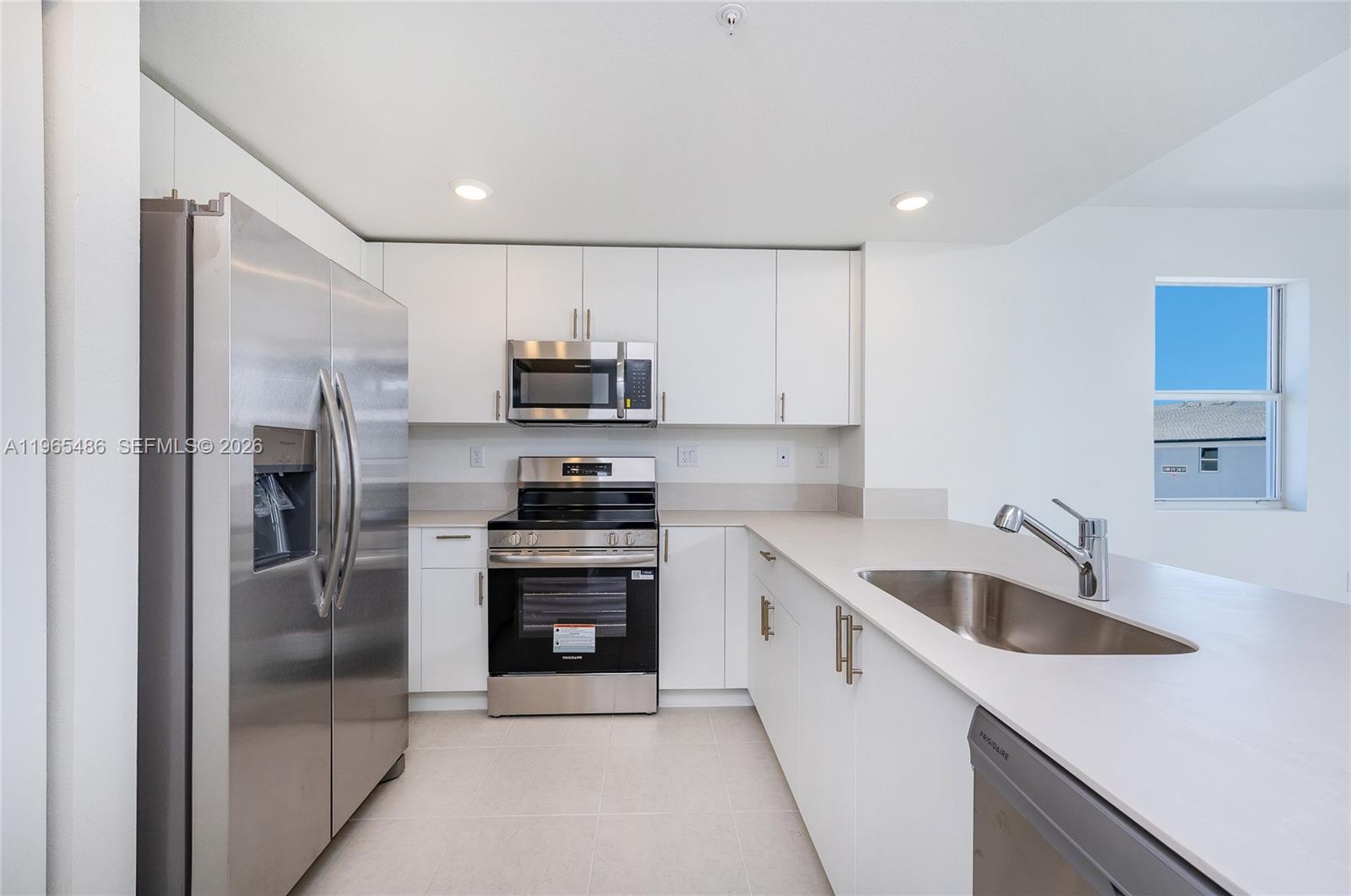 12470 Southwest 248th Street, Unit 1 Homestead, FL 33032 - Photo 9 of 35 a kitchen with kitchen island granite countertop a refrigerator stove and sink