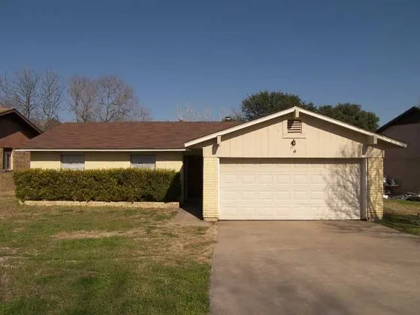 a front view of house along with road and trees