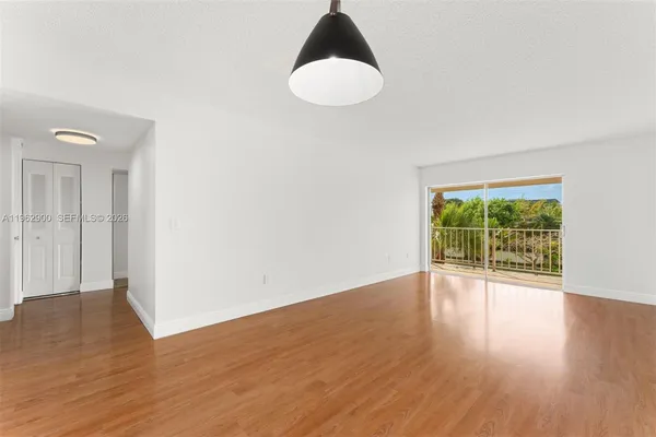 a view of an empty room with wooden floor and a window