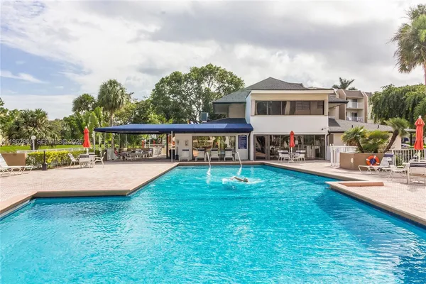 a view of swimming pool with lawn chairs and plants