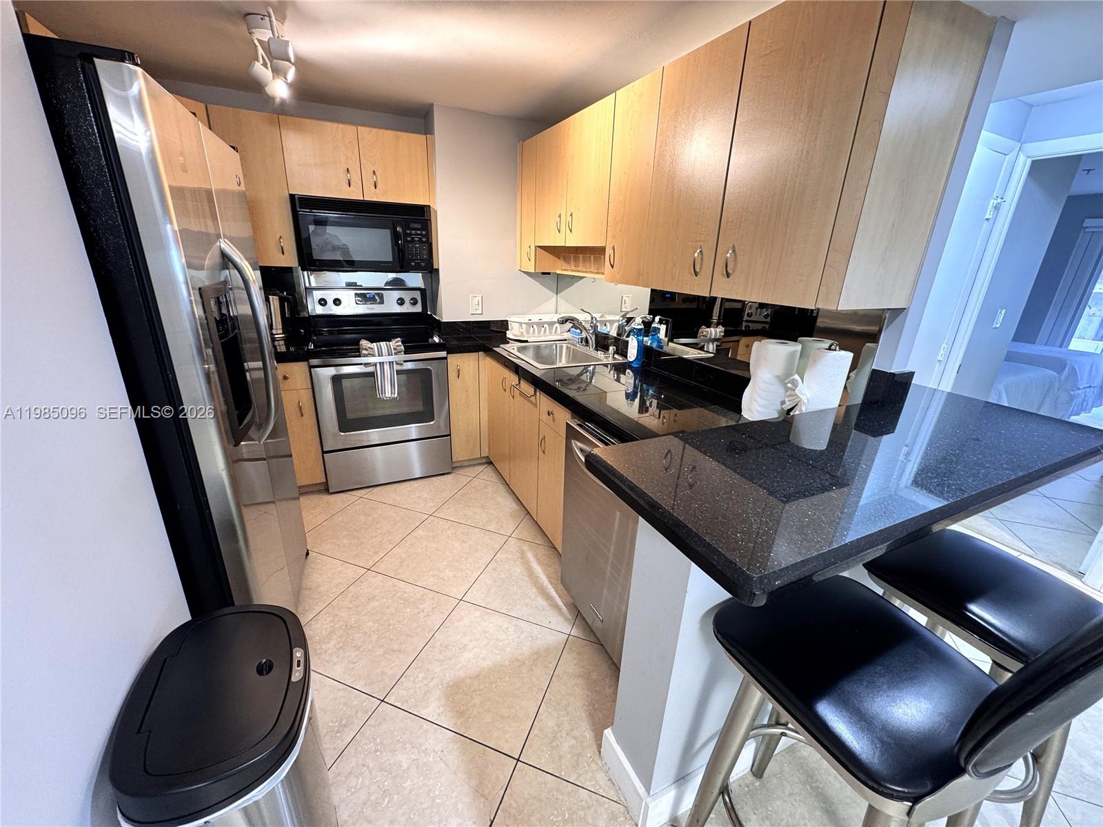 9195 Collins Avenue, Unit PH4 Surfside, FL 33154 - Photo 4 of 22 a kitchen with a sink a stove and chairs