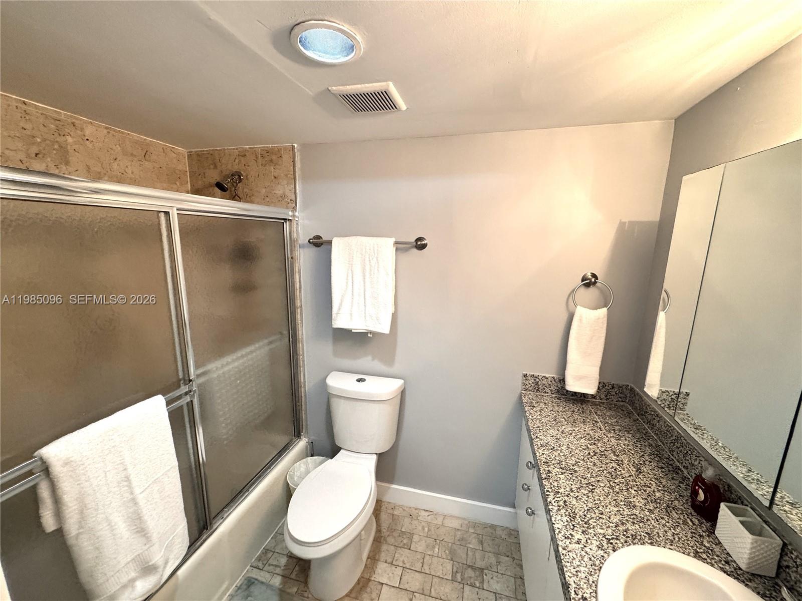 9195 Collins Avenue, Unit PH4 Surfside, FL 33154 - Photo 9 of 22 a white toilet sitting next to a bathroom sink and a mirror
