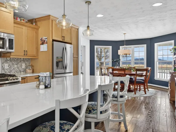 a kitchen with stainless steel appliances granite countertop a dining table chairs and granite counter tops