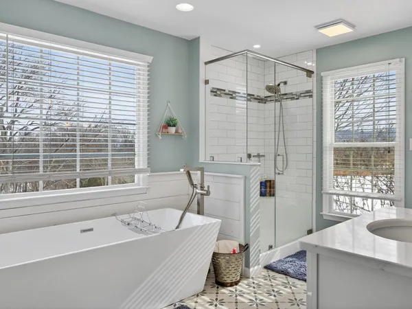 a bathroom with a tub a sink a window and a shower