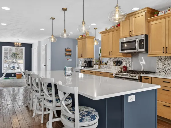 a kitchen with stainless steel appliances granite countertop a stove a sink a microwave a dining table and chairs with wooden floor