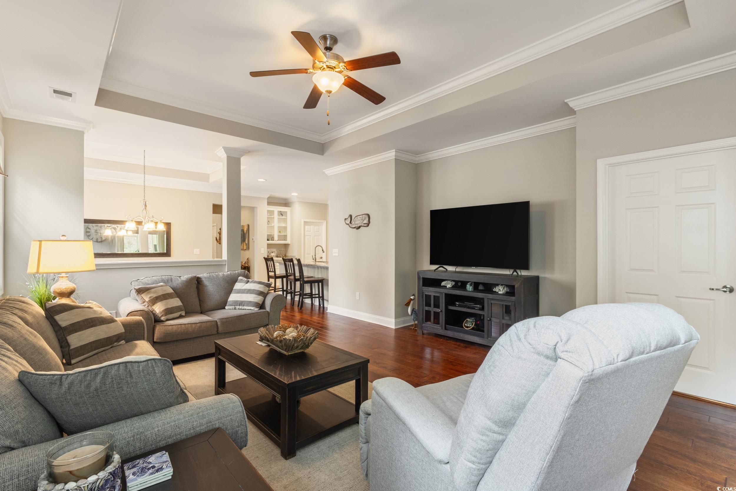 482 Botany Loop, Unit 155 Murrells Inlet, SC 29576 - Photo 20 of 40 Living area featuring a raised ceiling, wood finished floors, crown molding, a chandelier, and ceiling fan