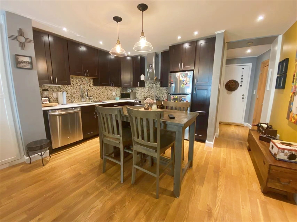 a kitchen with stainless steel appliances kitchen island granite countertop a table chairs refrigerator and microwave