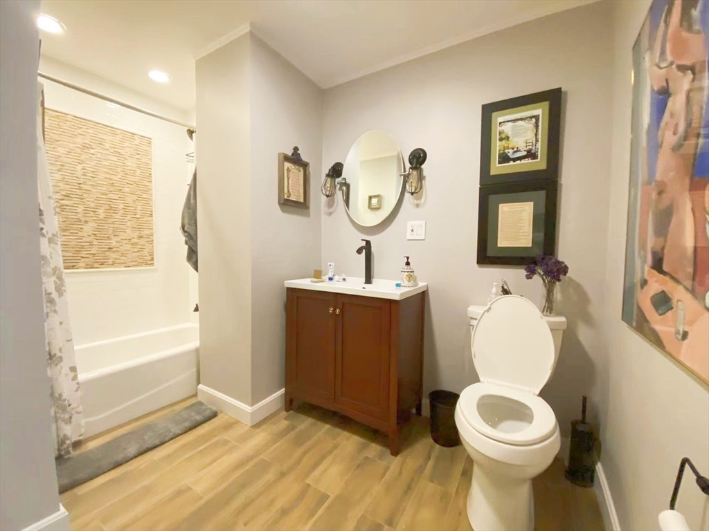 240 Heath Street, Unit 103 Boston, MA 02130 - Photo 7 of 10 a bathroom with a toilet sink and mirror