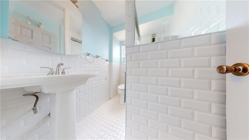 191 73rd Street, Unit 296 Brooklyn, NY 11209 - Photo 12 of 20 a bathroom with a sink a mirror and shower