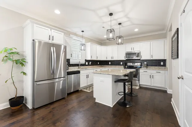 a kitchen with a refrigerator a sink dishwasher a stove and white cabinets with wooden floor