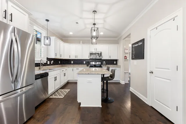 a open kitchen with a table chairs refrigerator and wooden floor