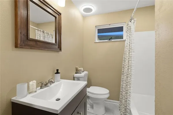 a bathroom with a sink a toilet and shower curtain