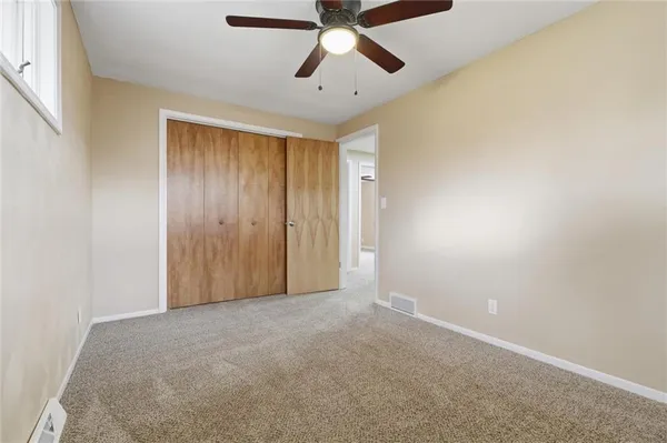 an empty room with a ceiling fan and a window