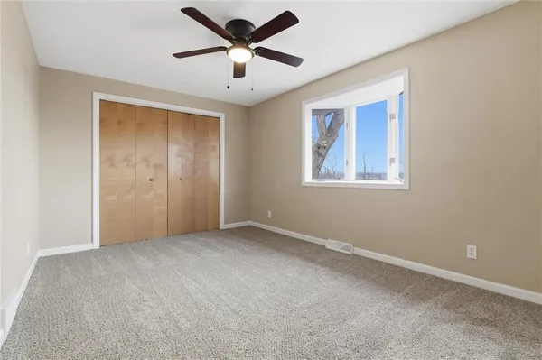 an empty room with closet and a chandelier fan