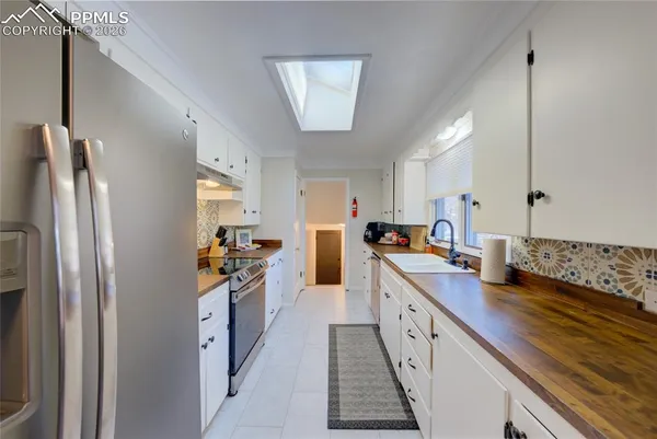 a kitchen with stainless steel appliances granite countertop a refrigerator a stove and a sink