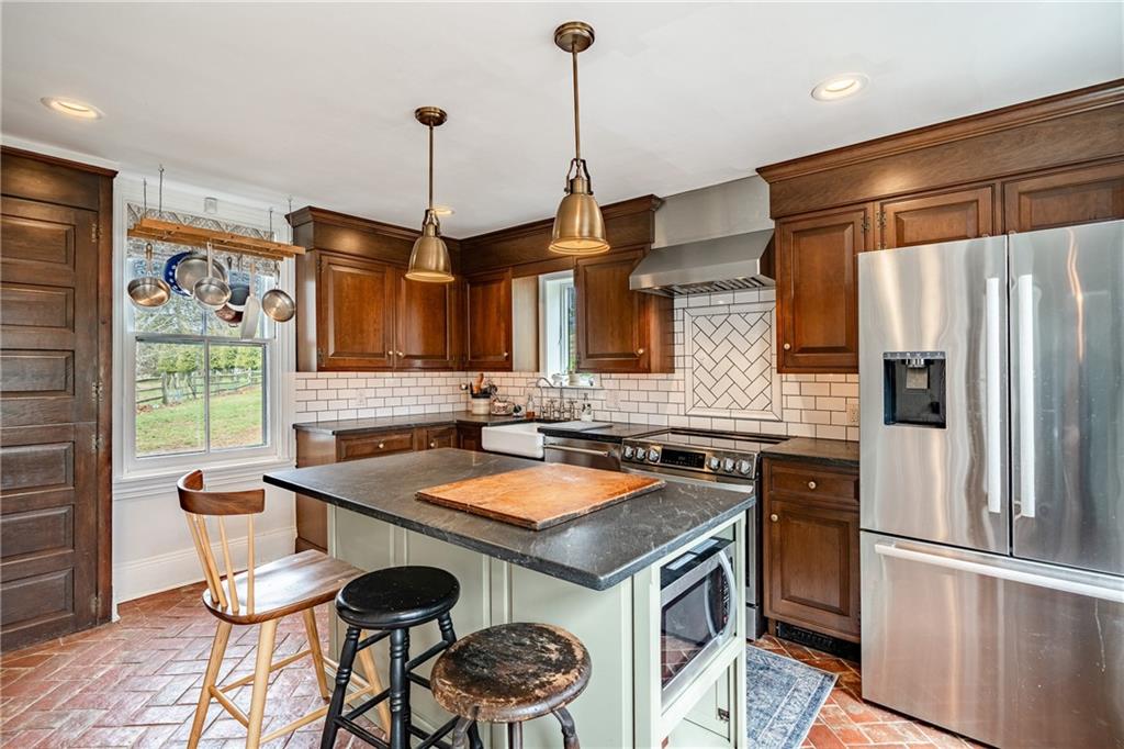 701 Oakbourne Road West Chester, PA 19382 - Photo 16 of 50 a kitchen with stainless steel appliances granite countertop a stove a refrigerator a sink a dining table and chairs with wooden floor