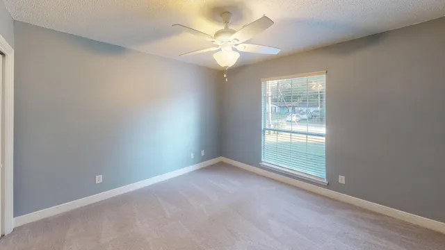 an empty room with windows and chandelier fan