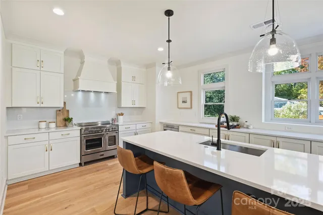 a large kitchen with granite countertop a stove a sink a dining table and chairs with wooden floor