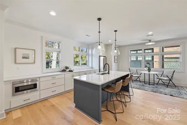 a kitchen with stainless steel appliances granite countertop a stove a sink a dining table and chairs with wooden floor