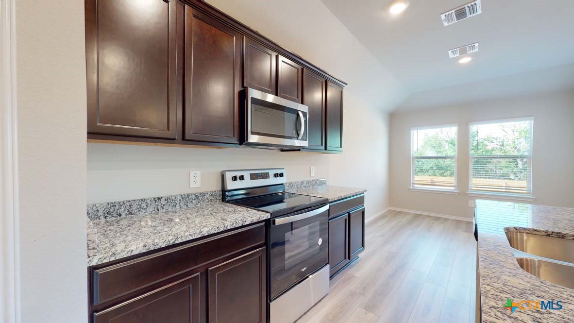 549 Hector Loop Georgetown, TX 78626 - Photo 4 of 22 a kitchen with granite countertop wooden cabinets stainless steel appliances and a window