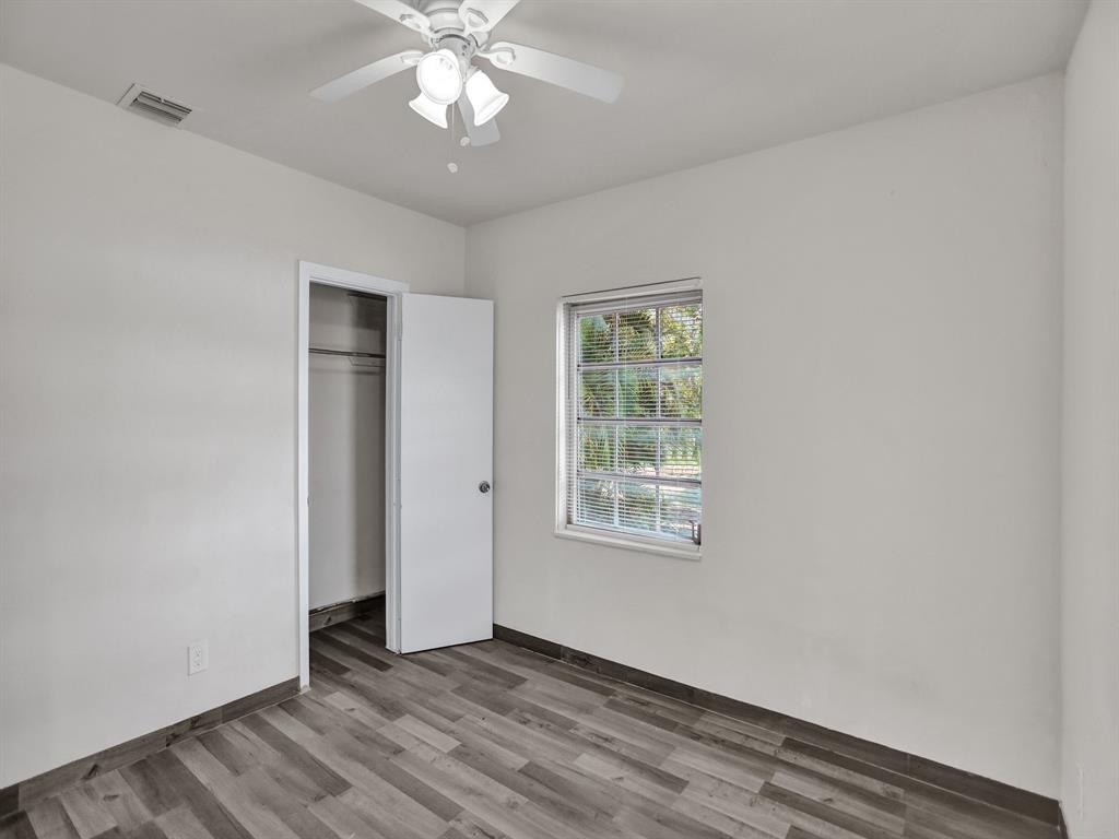 535 Northwest 91st Street, Unit 2 Miami, FL 33150 - Photo 15 of 20 an empty room with wooden floor chandelier fan and windows