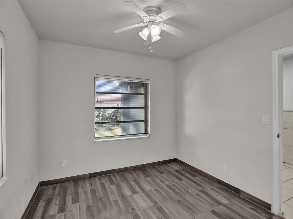 535 Northwest 91st Street, Unit 2 Miami, FL 33150 - Photo 16 of 20 an empty room with wooden floor chandelier fan and windows