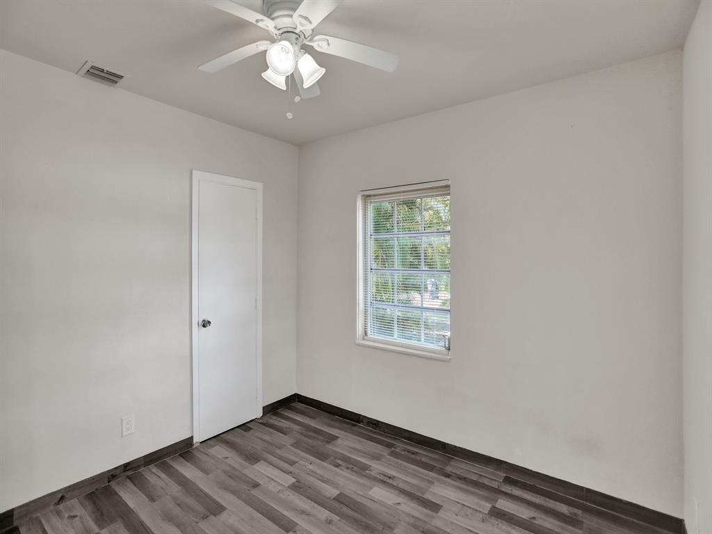 535 Northwest 91st Street, Unit 2 Miami, FL 33150 - Photo 18 of 20 an empty room with wooden floor chandelier fan and windows
