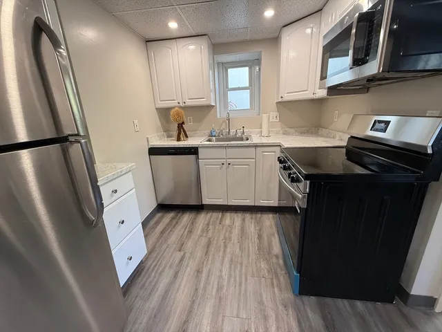 a kitchen with a sink a refrigerator a microwave and cabinets