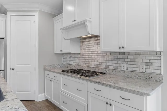 a large kitchen with a refrigerator a sink and a wooden floor