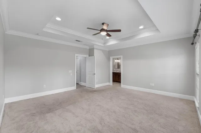 a view of a livingroom with a ceiling fan & windows