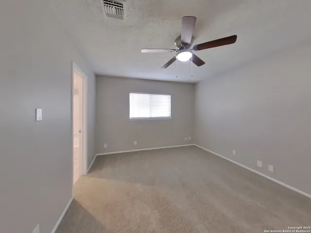 an empty room with windows and fan