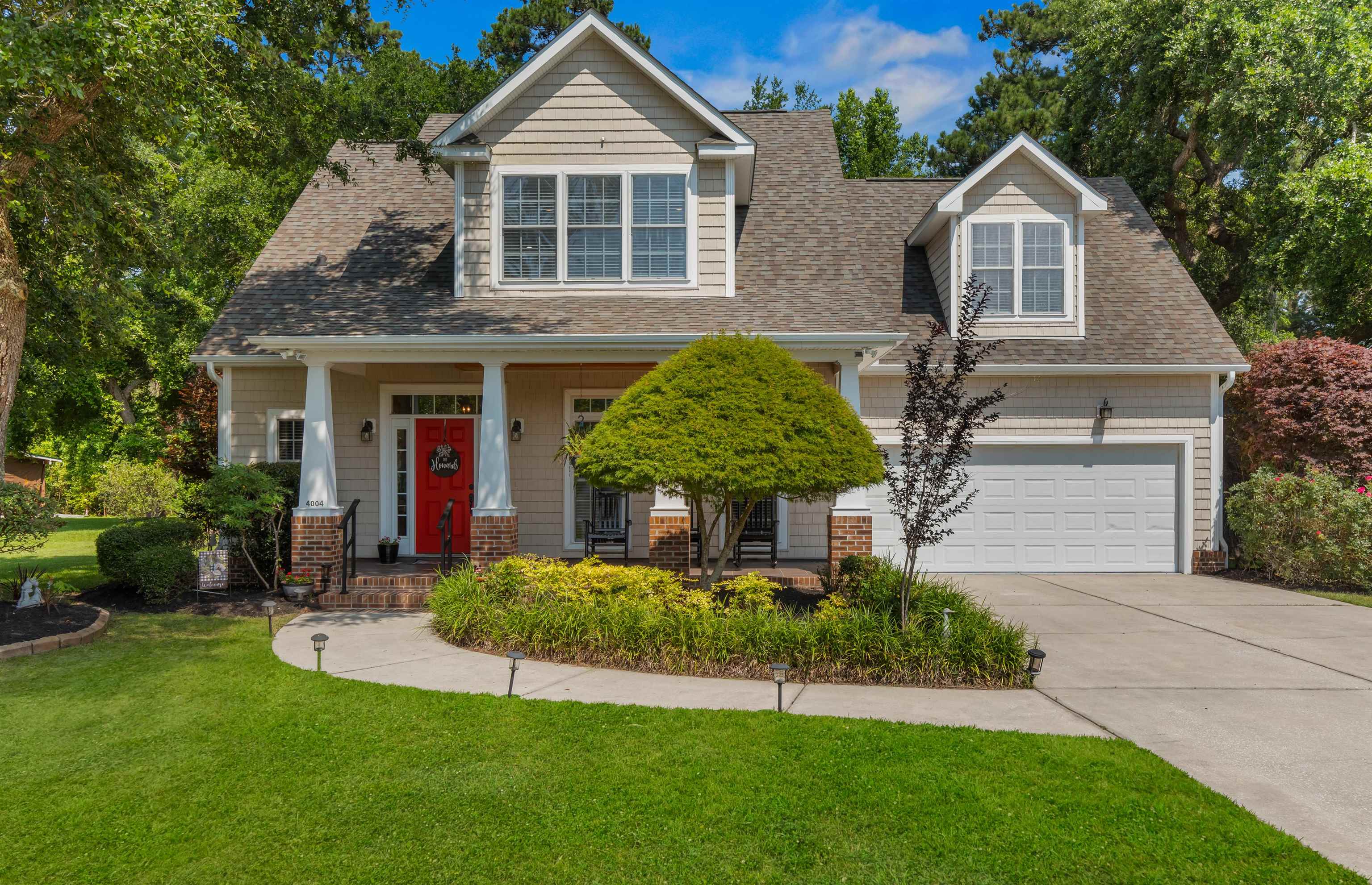 View of front of house with driveway, a shingled roof, a front lawn, a garage, and covered porch